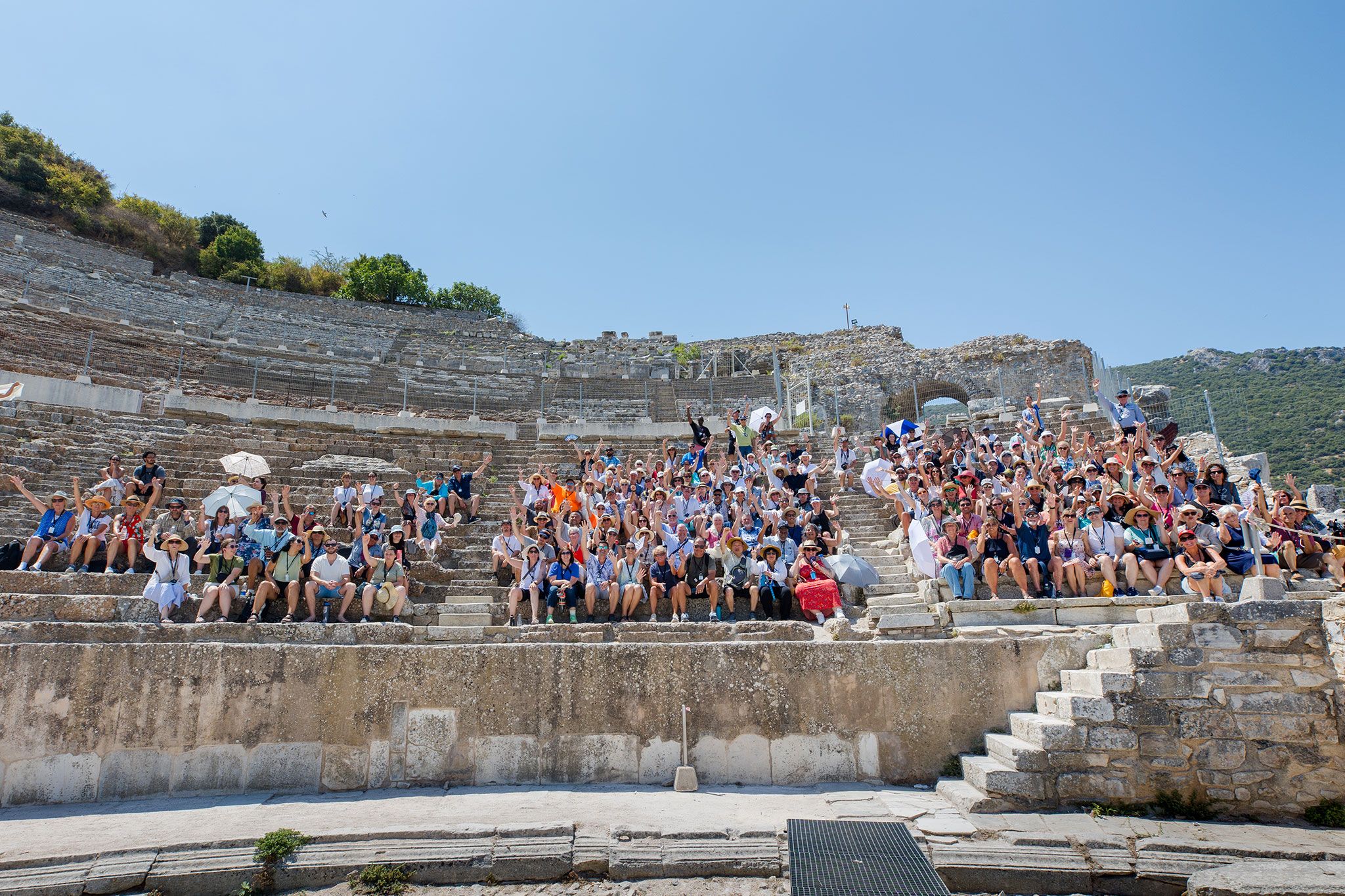 A diverse crowd of Christian travelers gathered on the historic amphitheater steps at Ephesus, posing for a group photo.