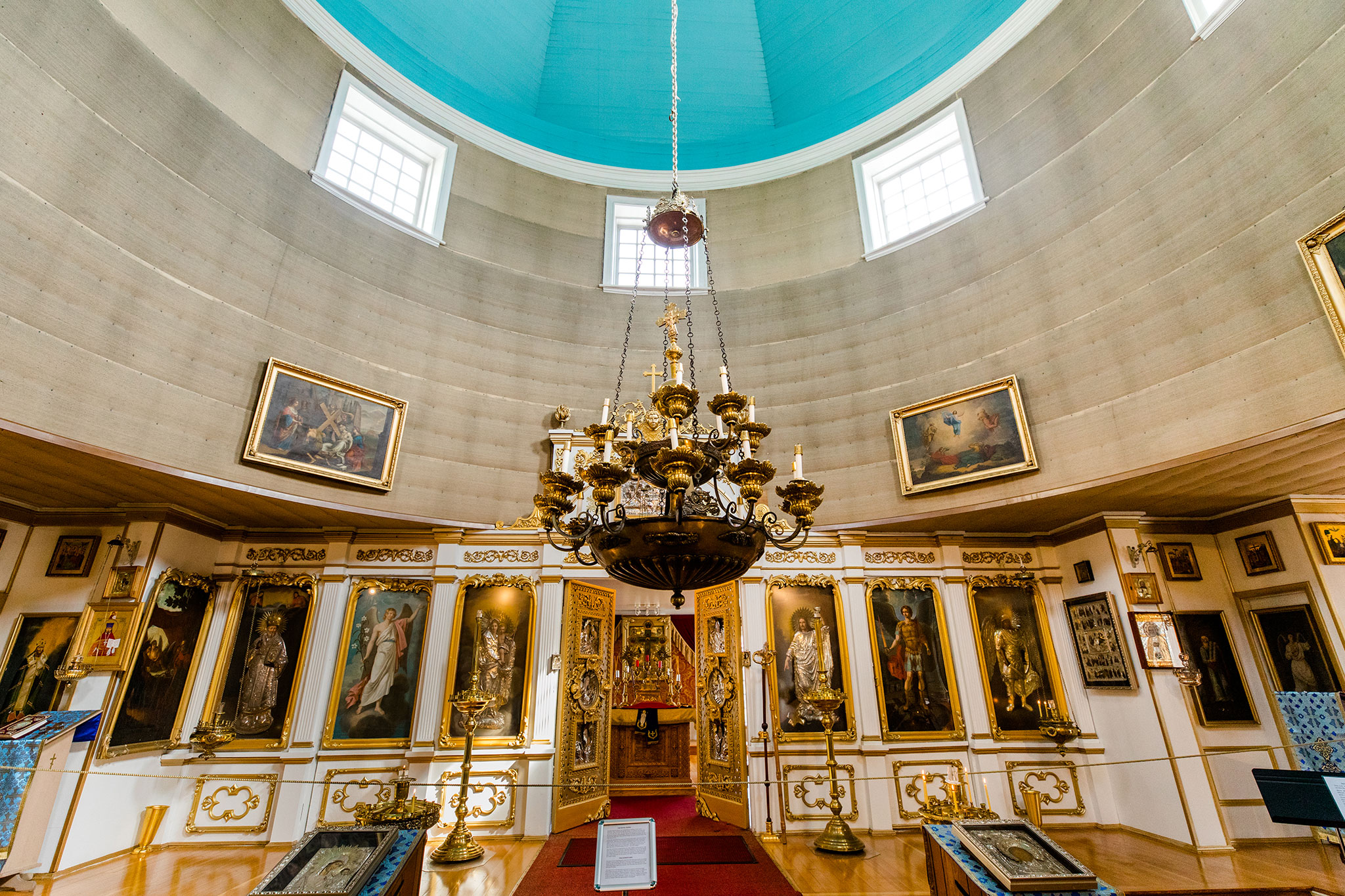 Richly decorated church sanctuary with a blue dome and a large golden chandelier.