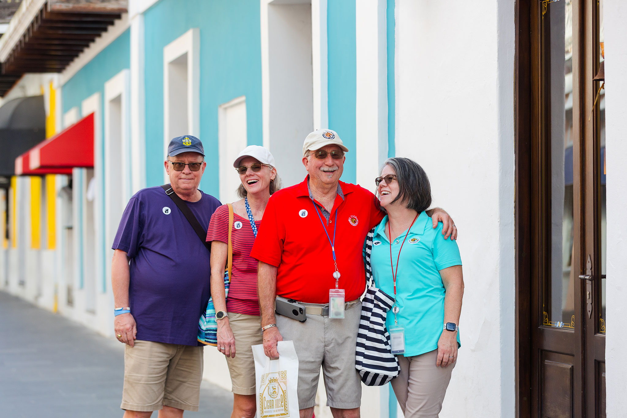 Four smiling Christian travelers in casual gear pose together on a colorful street while exploring Old San Juan.
