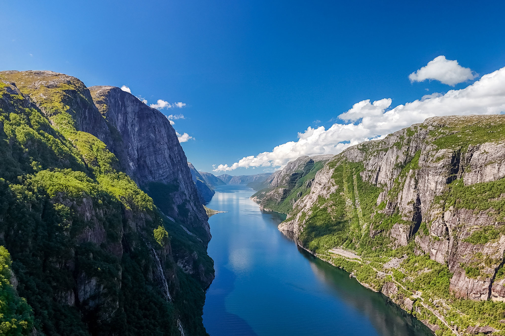 Panoramic scene of Lysefjord showing rugged mountainsides, sheer cliffs, and reflective fjord waters winding through the valley.
