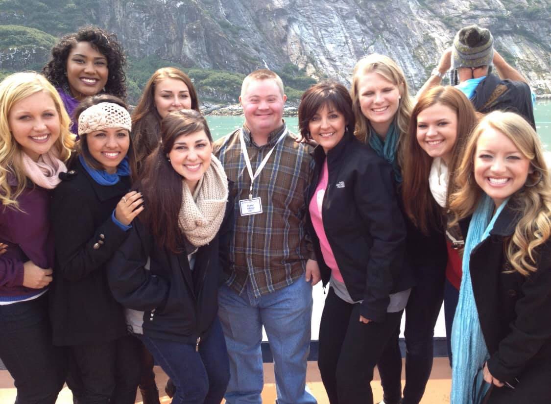 Group of smiling people standing together on the deck of a cruise ship in Alaska