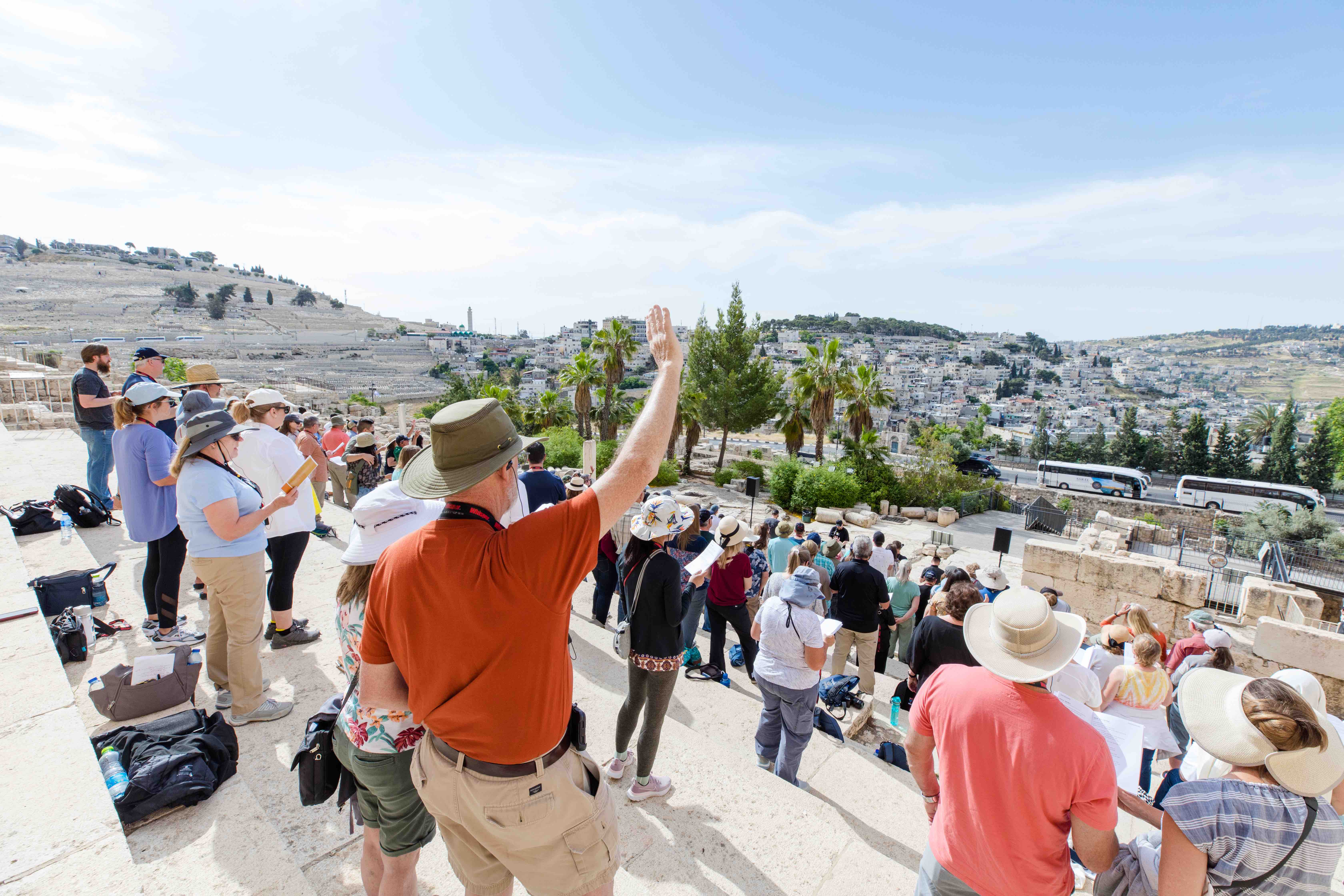 Group of people on the Southern Steps. Man in red shirt lifting one hand up.