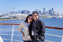 Couple on cruise deck with Seattle skyline behind them.