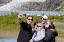 Group of travelers smiling for a selfie with beautiful greenery and glaciers in the background