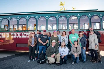 Group of travelers standing to together in front of a trolley car