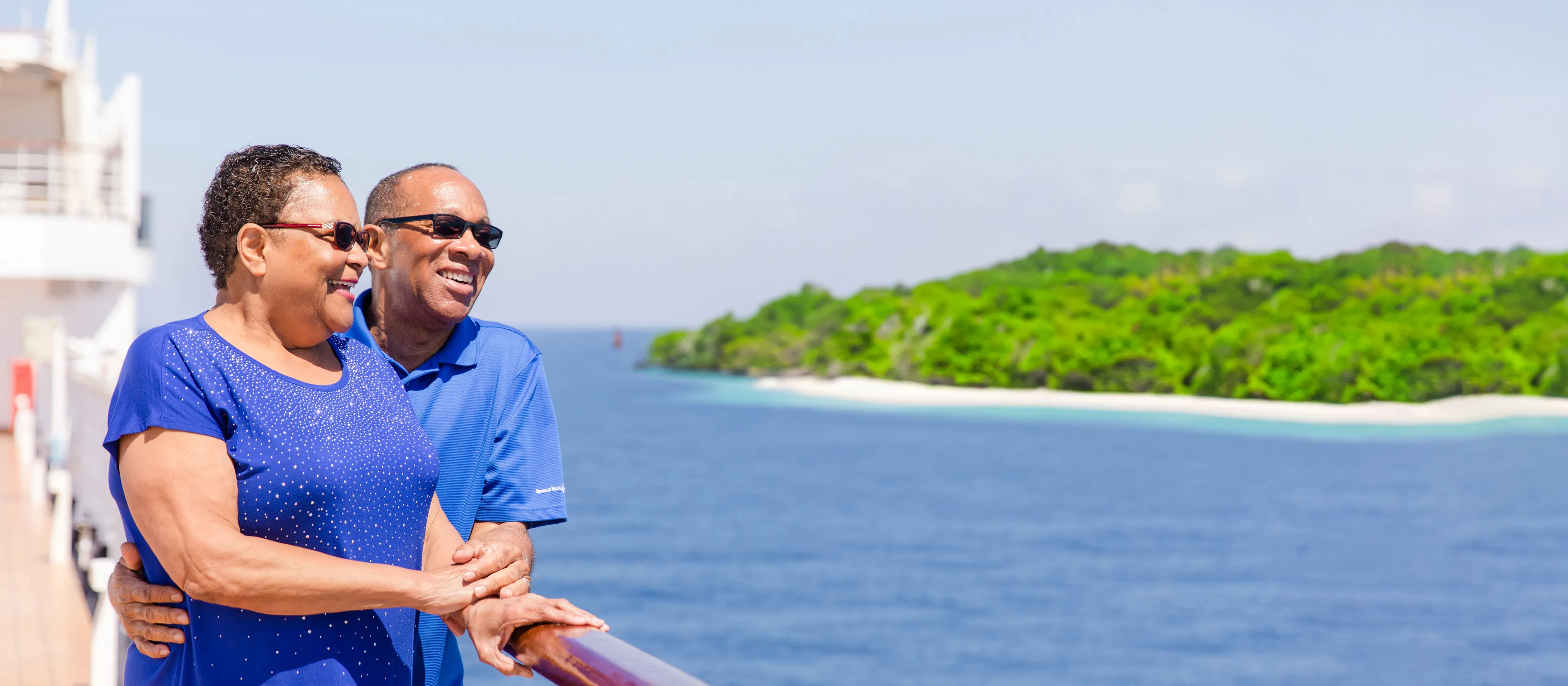 A couple standing together on the ship deck overlooking the ocean