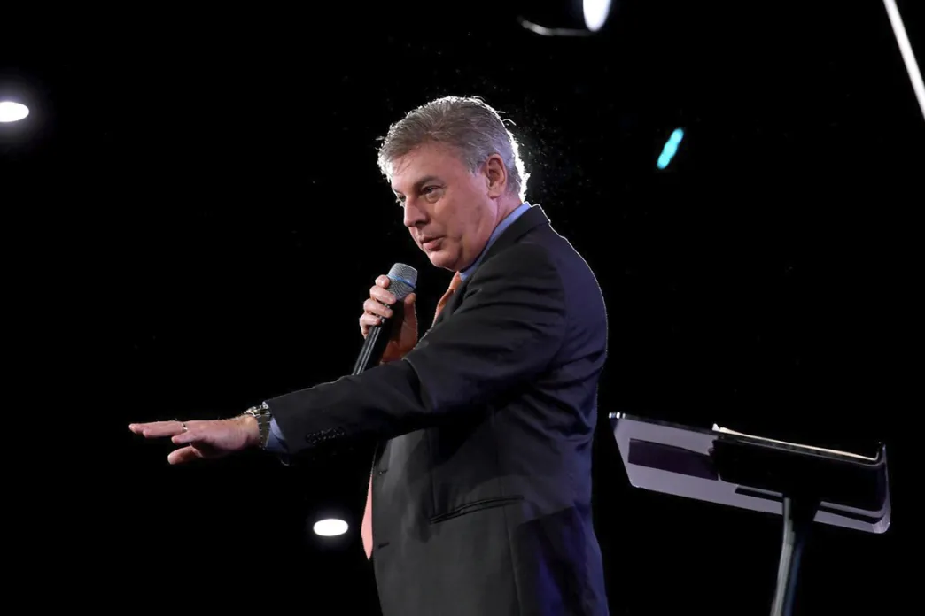 Lance Wallnau holding a microphone and speaking on a stage
