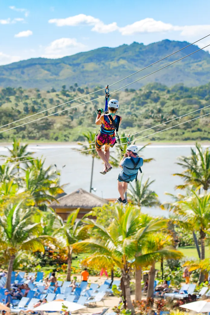 Zip lining over palm trees towards the ocean coast