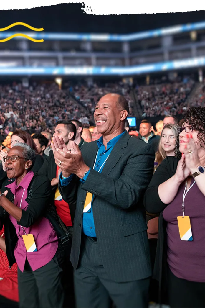 Large crowd of clapping, smiling people in an auditorium