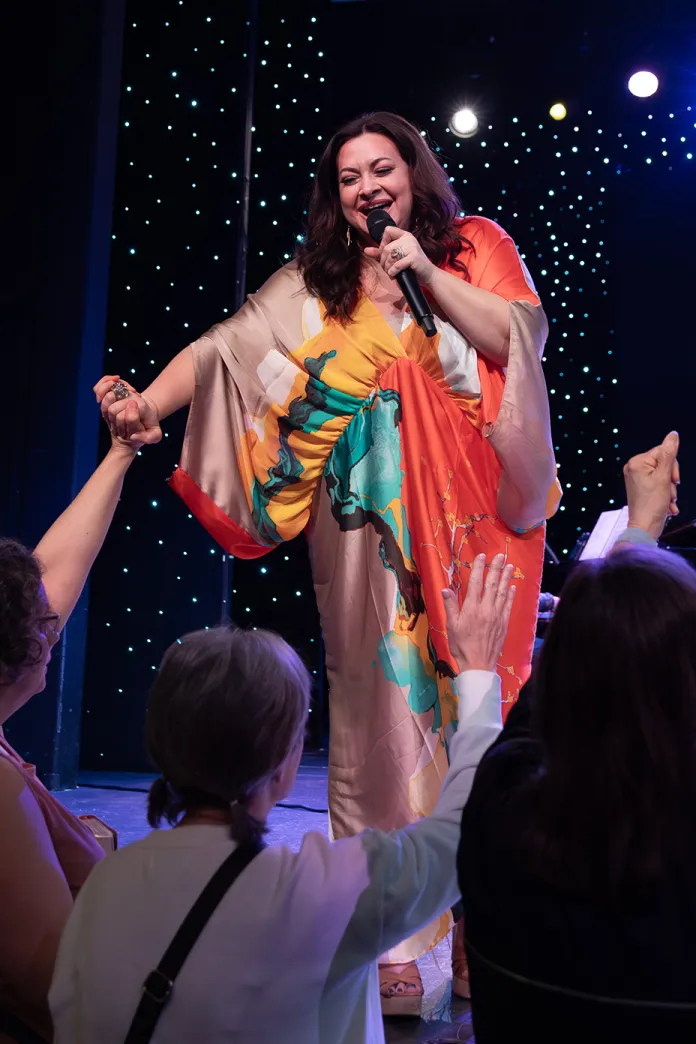 Taranda singing on stage while holding the hand of an audience member