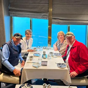 Group of four smiling travelers sitting at a table eating