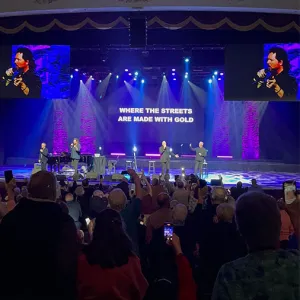 Singers on a colorful stage performing to an auditorium full of people