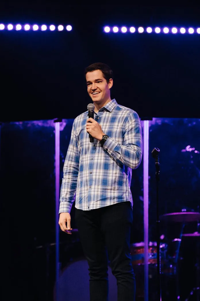 Andrew Stanley standing on a stage, holding a microphone 