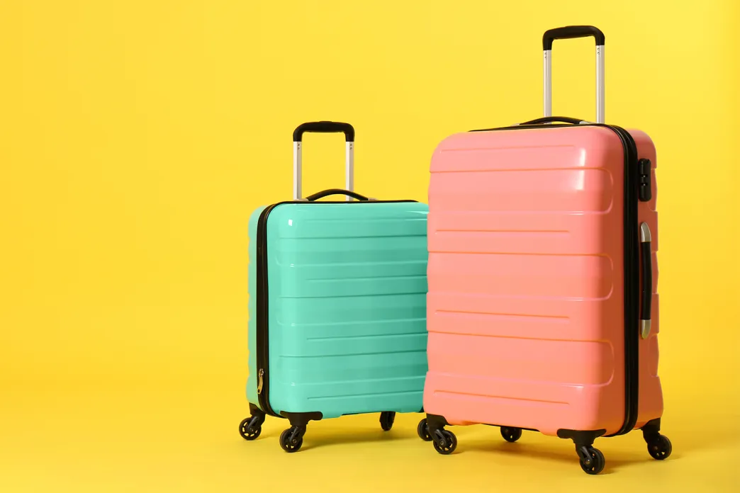 Blue and pink luggage with a yellow background